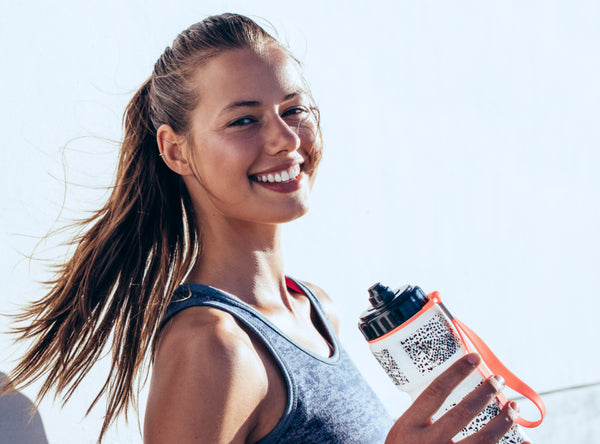 Fit Woman Smiling While Holding a Water Bottle